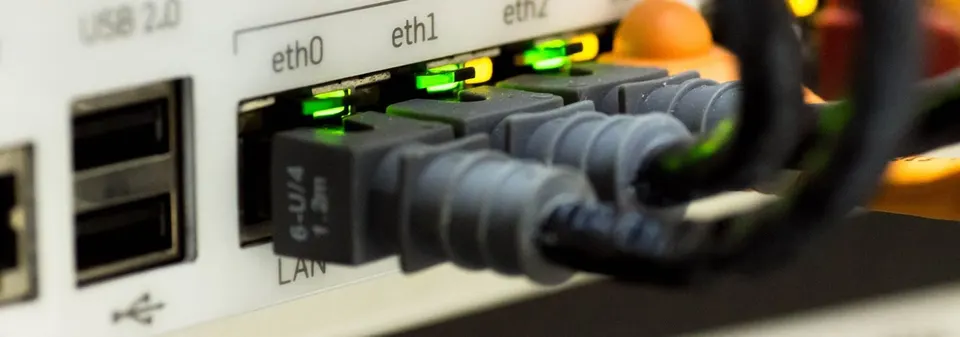 Close-up of network cables plugged into the LAN ports of a router, with green status lights lit.