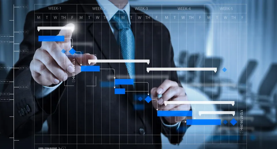 A manager in a suit points at a project schedule shown as a Gantt chart on a virtual screen.